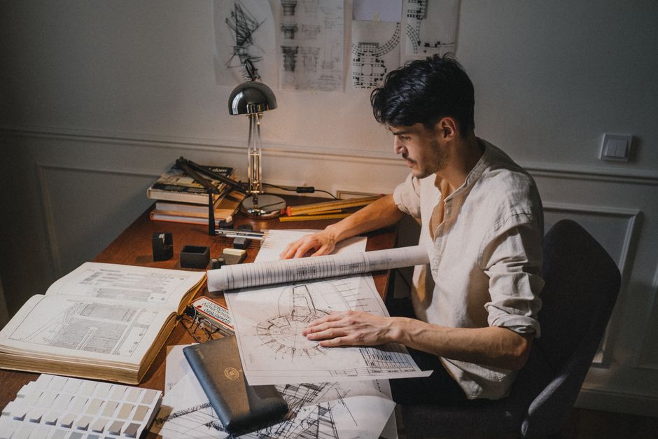 A designer's workspace featuring colored pencils, sticky notes, and printed layout templates arranged neatly.